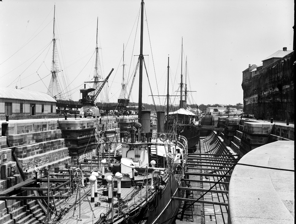 A steel ship propped in a stone dry dock for inspection and repair, photographed around 1900